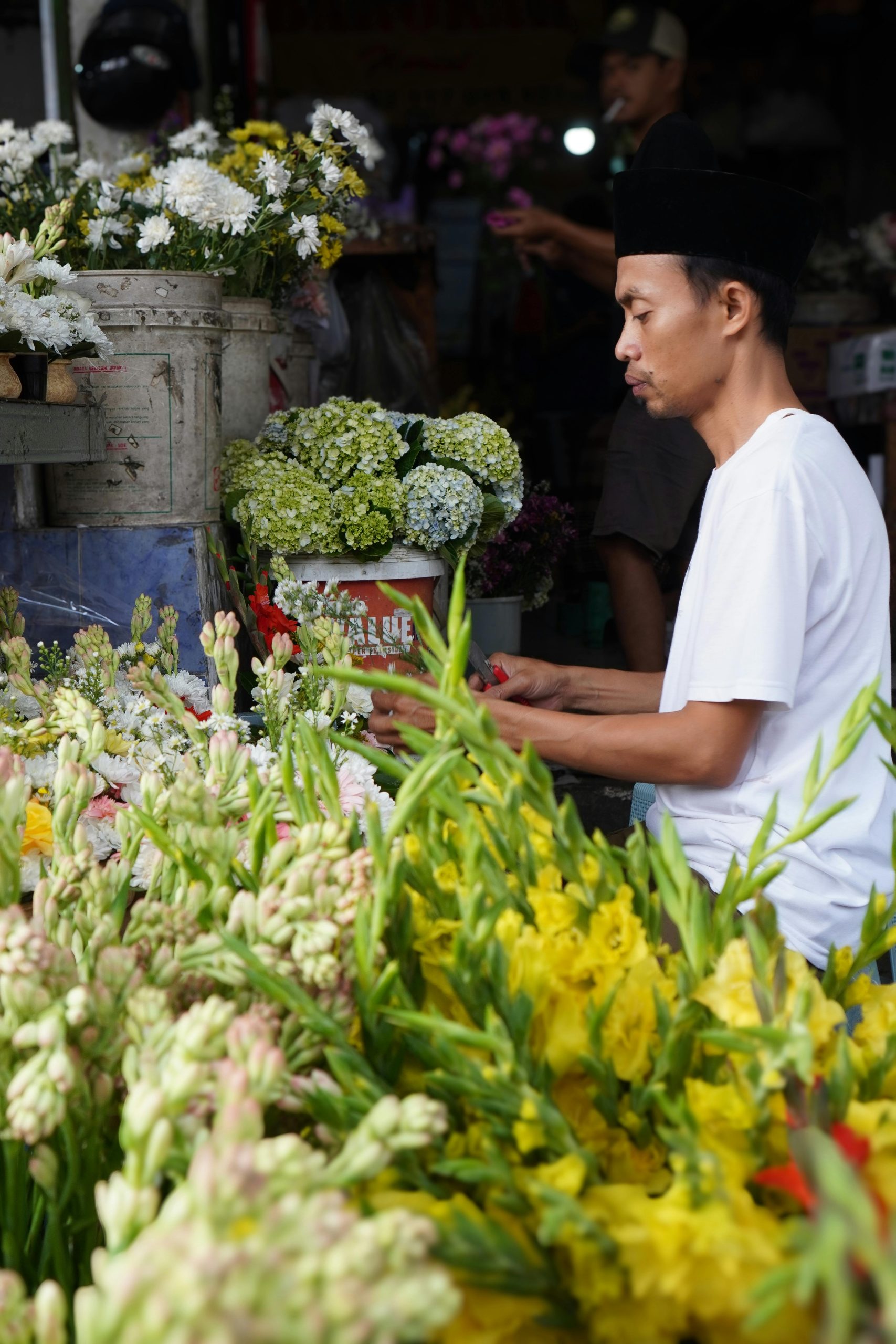 Florist carefully organizing yellow and white flowers at a busy market stall.
